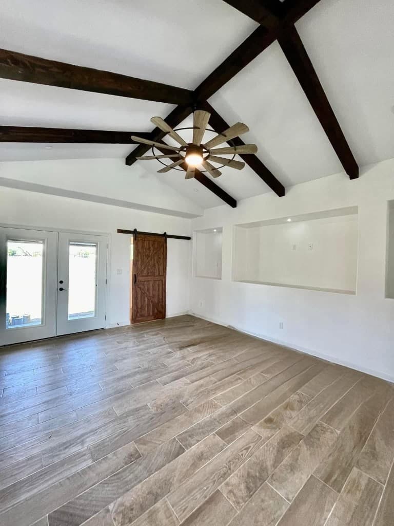 Living room with vaulted ceiling, wood beams, and barn door