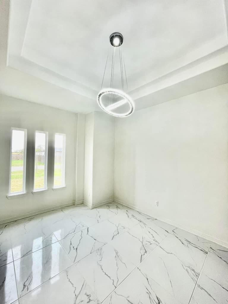 Finished interior room with marble flooring and tray ceiling