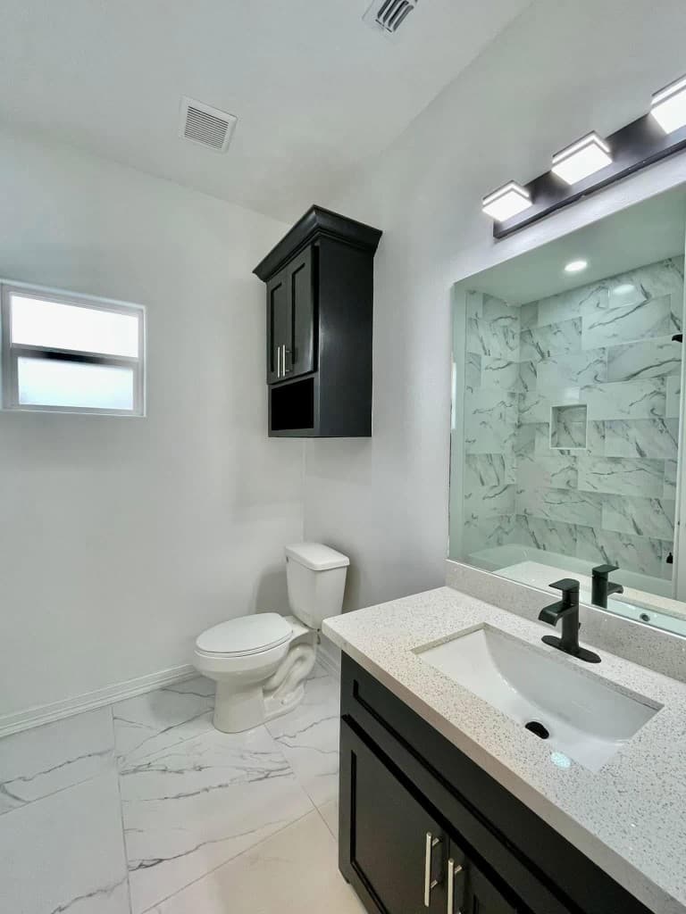 Modern bathroom renovation with black vanity and marble tile