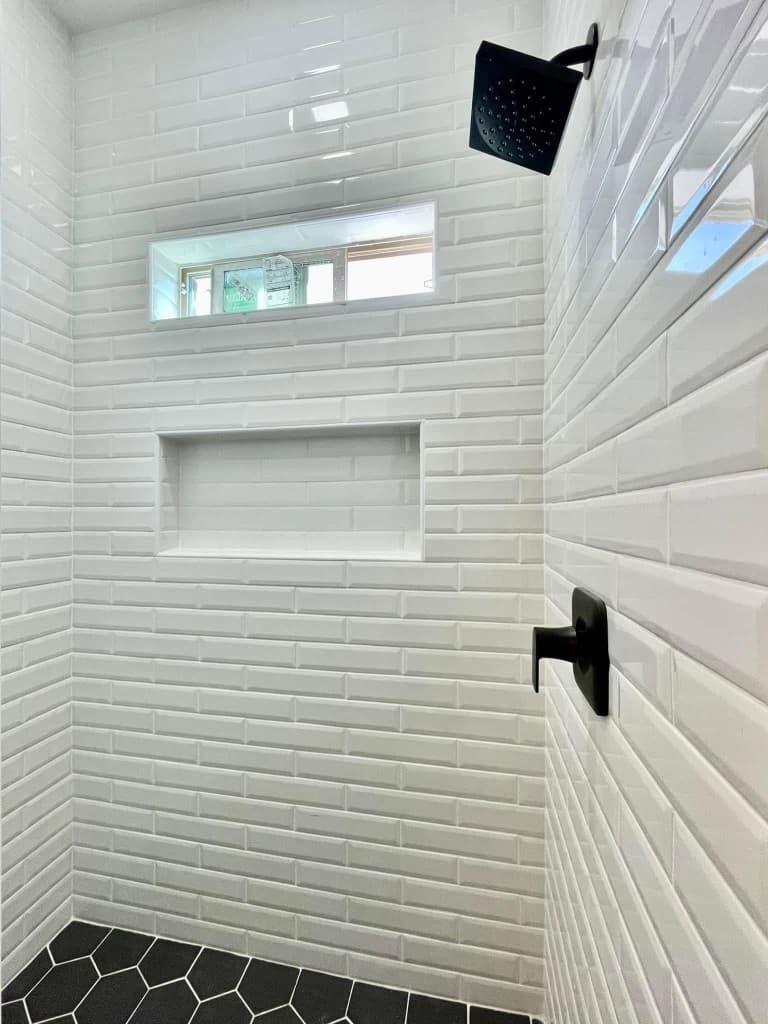 Custom shower with white subway tile and black hex floor